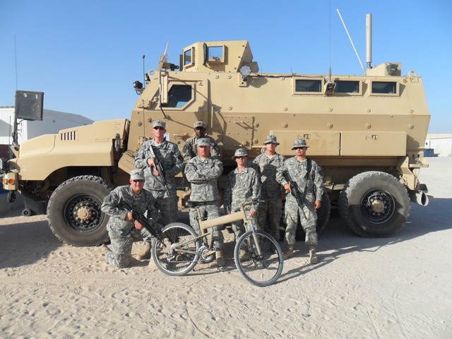 Paratrooper folding bike and soldiers in front of vehicle